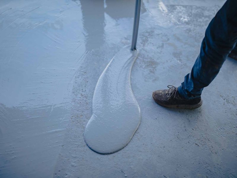 The worker applies gray epoxy resin to the new floor