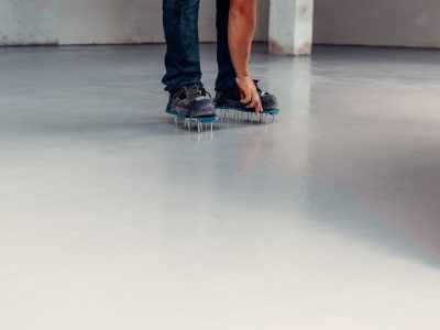 A construction worker apply grey epoxy resin in an industrial hall
